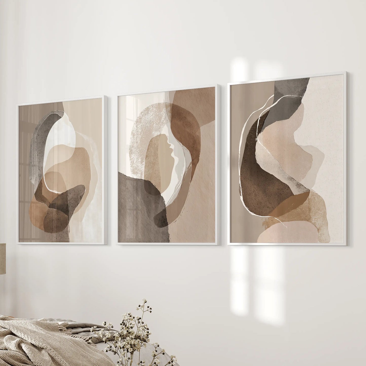 Three-piece wall picture set of earth-tone geometric prints in white frames balances the bed wall with soft taupe and brown tones.