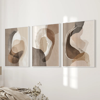 Three-piece wall picture set of earth-tone geometric prints in white frames balances the bed wall with soft taupe and brown tones.