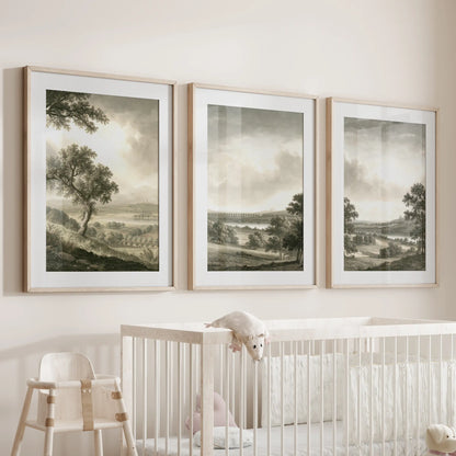 Pastoral landscape wall art in a set of three, with matted prints in thin wood frames above a cot in a baby nursery.