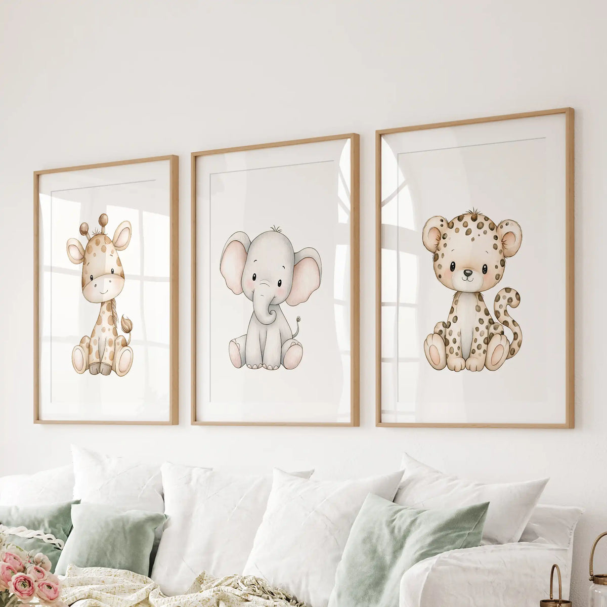 The three animal prints above a sofa show a giraffe, elephant and spotted leopard, surrounded by white mats and oak frames.