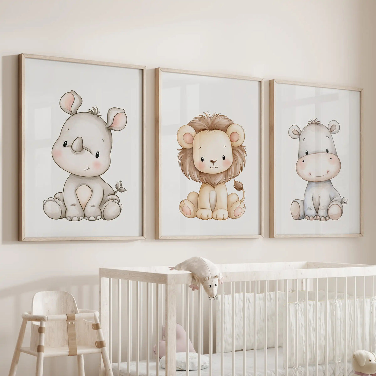 Above a nursery crib hangs a set of three prints showing a pale rhino and gray hippo beside a small lion, framed in oak.