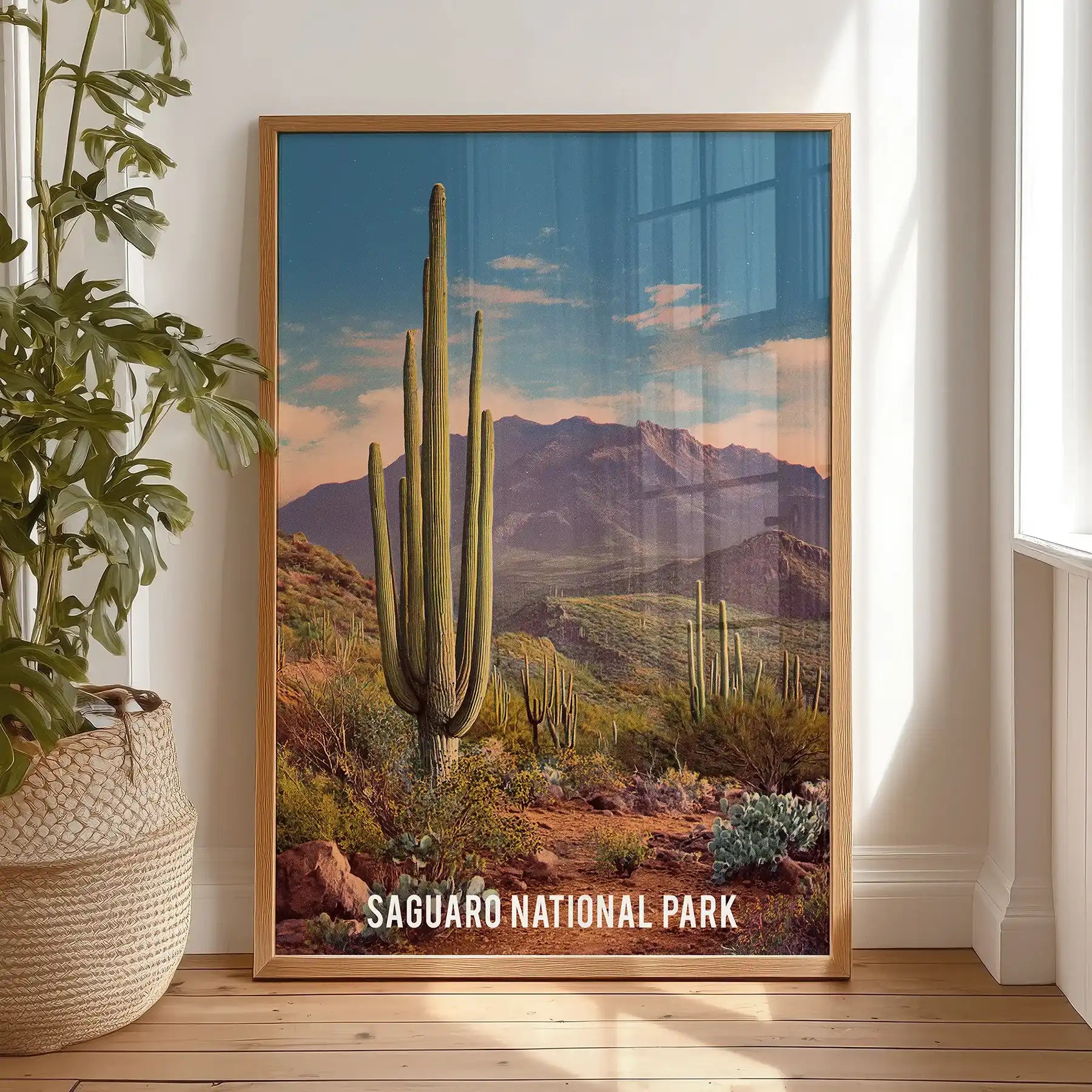 Warm wood-framed wall art of Arizona wilderness stands on the bedroom floor by the window, inviting a calm, open-air view indoors.