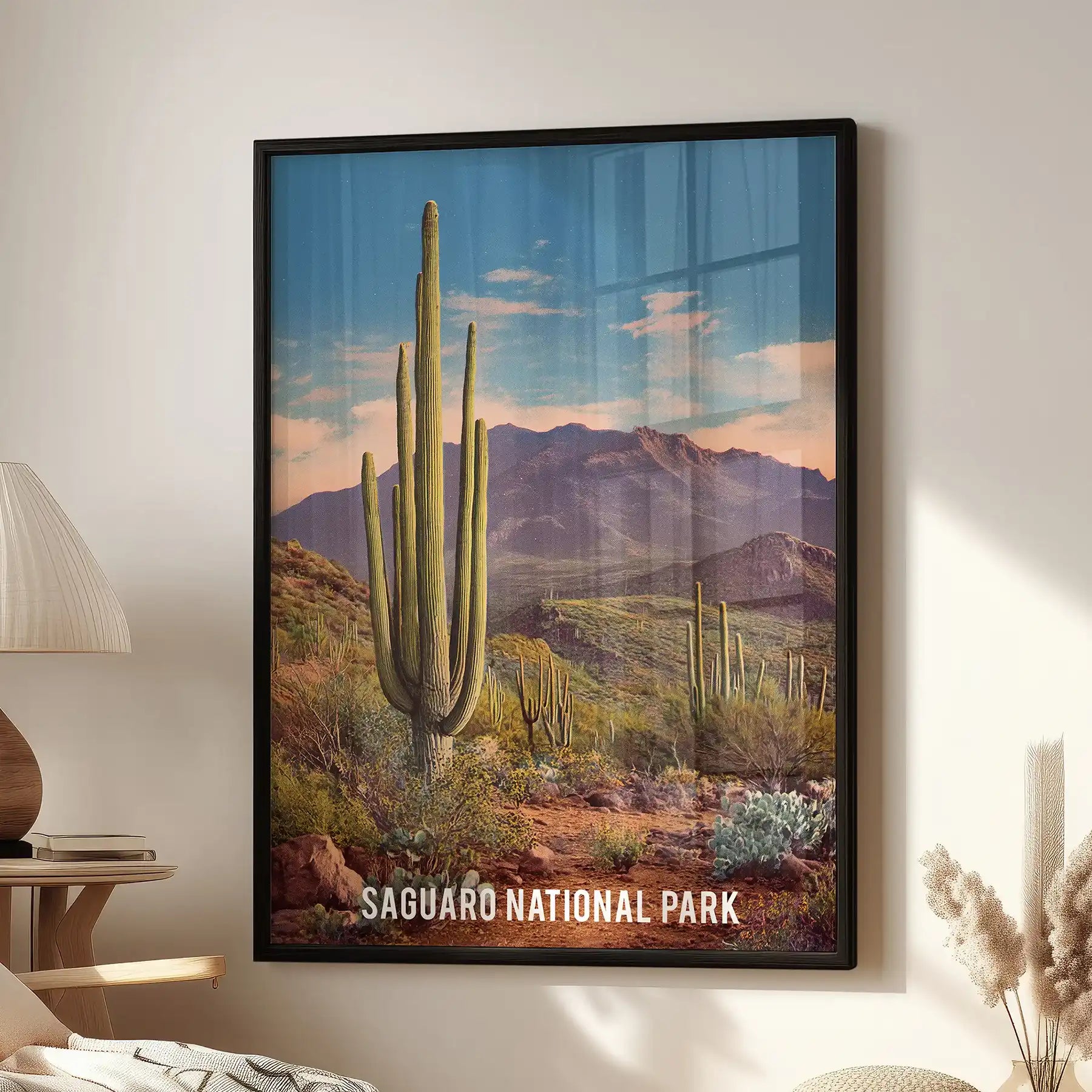 A black-framed wall art print featuring tall saguaro cacti hangs above the living-room window beside a side chair for a sleek finishing touch.