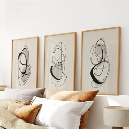 Black and beige abstract shapes, a wall art trio in light wood frames, centered above the bed headboard for a soft, Scandinavian calm.