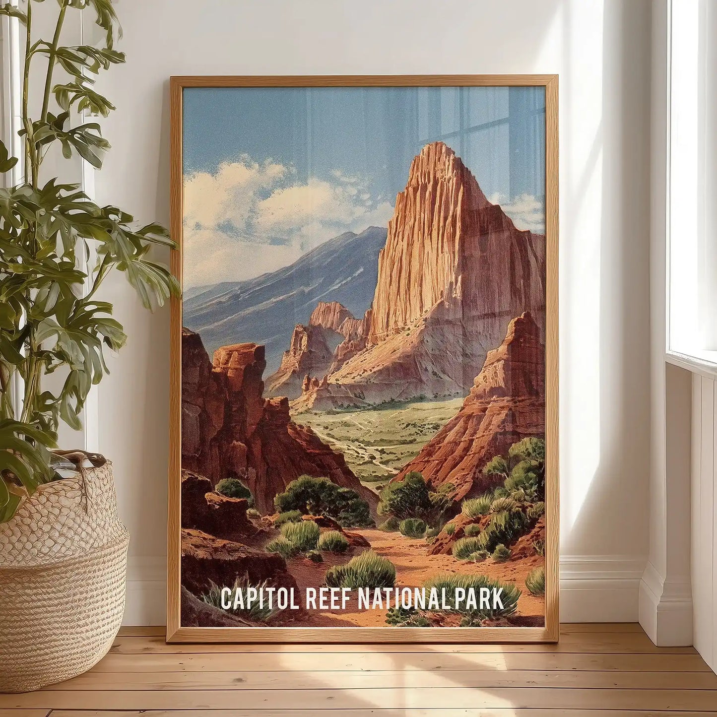 Gallery-style wall art of Utah’s cliffs rests in a light wood frame on the bedroom floor by the window, lending a calm, natural feel.