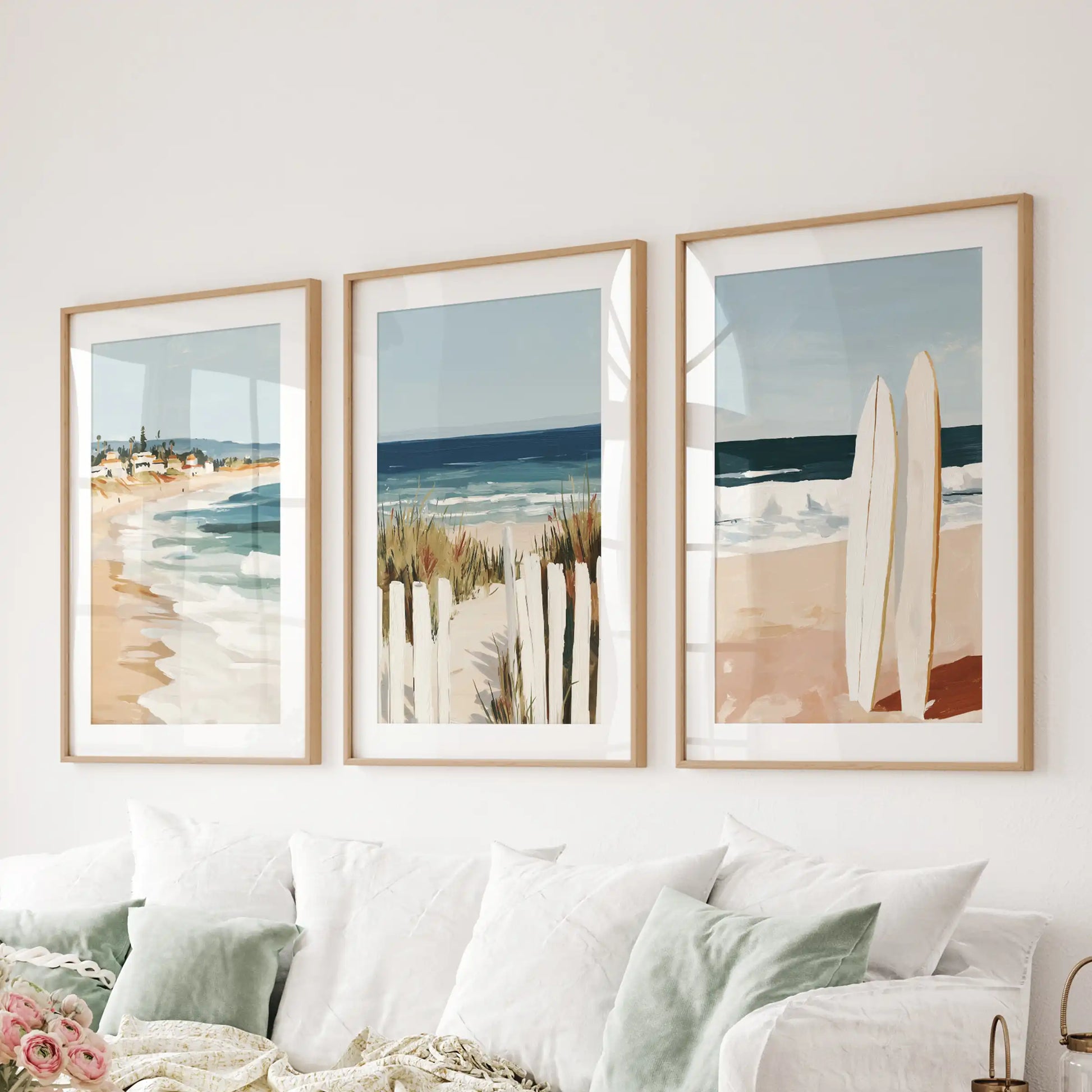 Sandy shoreline gallery wall of three hangs over the couch, washing the lounge in sunlit neutrals within oak frames with mats.