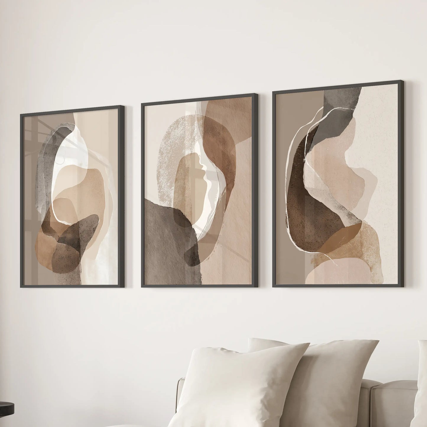 Minimalist wall decor of three beige and brown prints in sleek black frames stretches over a family-room couch for a composed look.