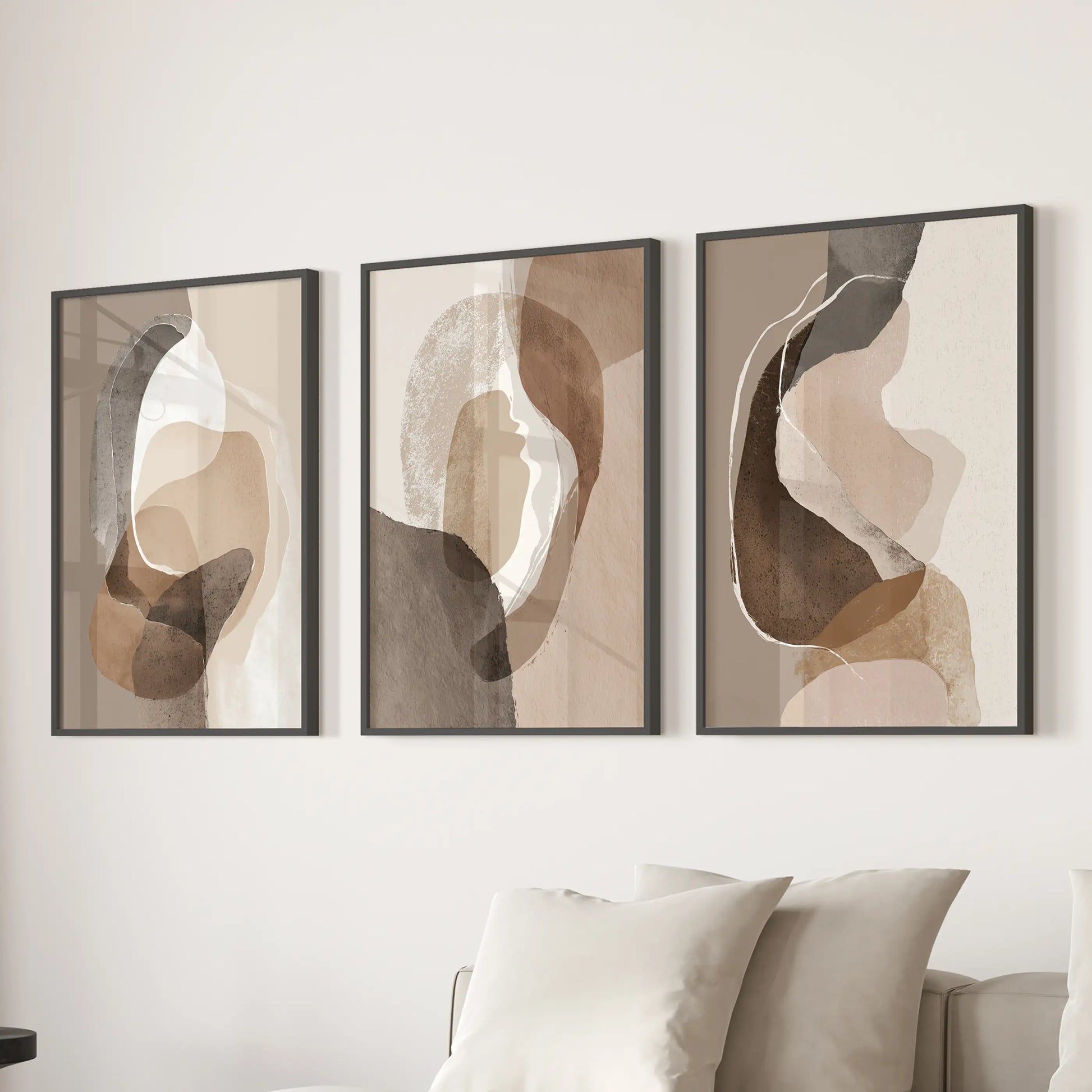 Minimalist wall decor of three beige and brown prints in sleek black frames stretches over a family-room couch for a composed look.