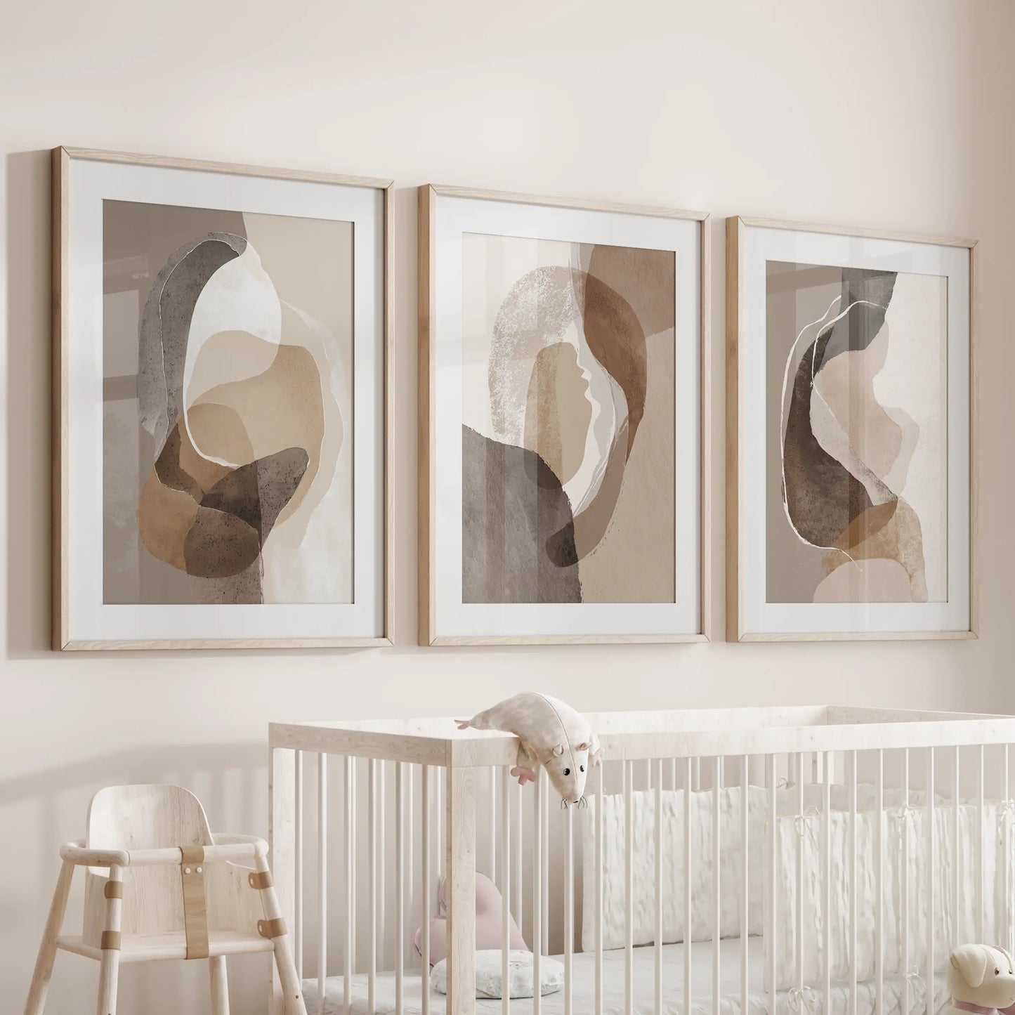 Set of three oak-framed wall art prints, matted and softly toned, hovers over a nursery cot to introduce gentle earth colors.