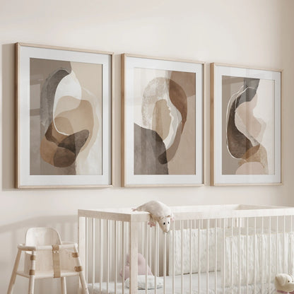 Set of three oak-framed wall art prints, matted and softly toned, hovers over a nursery cot to introduce gentle earth colors.