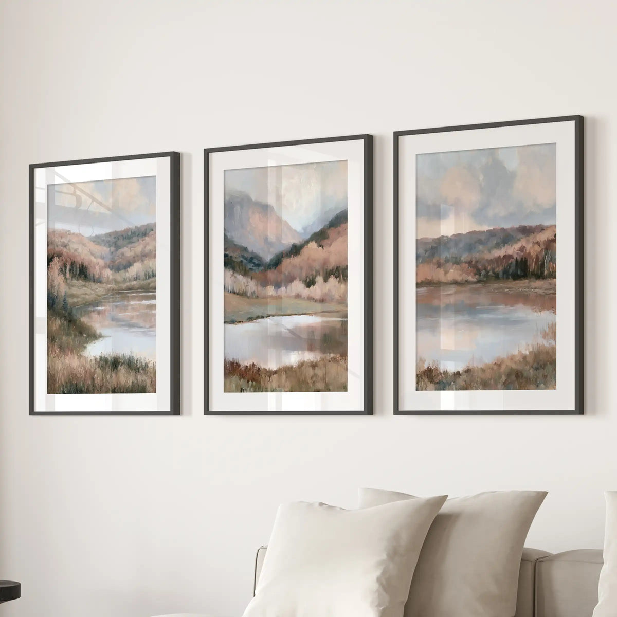 Three wall artworks of water reflections and shoreline trees, with black mats and frames, hang above the lounge sectional as a serene focal point.