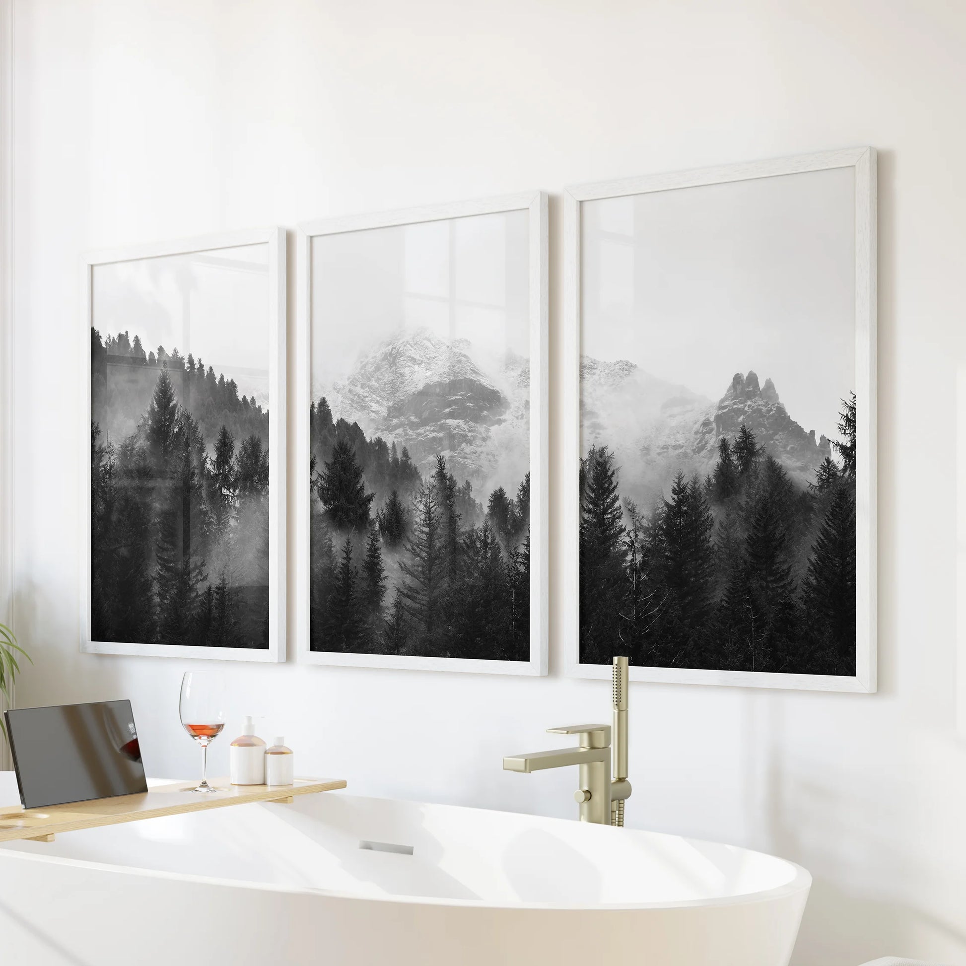 Cloud-shrouded peaks over forest set of three white-framed wall prints, calming artwork for the bathroom above a soaking tub.