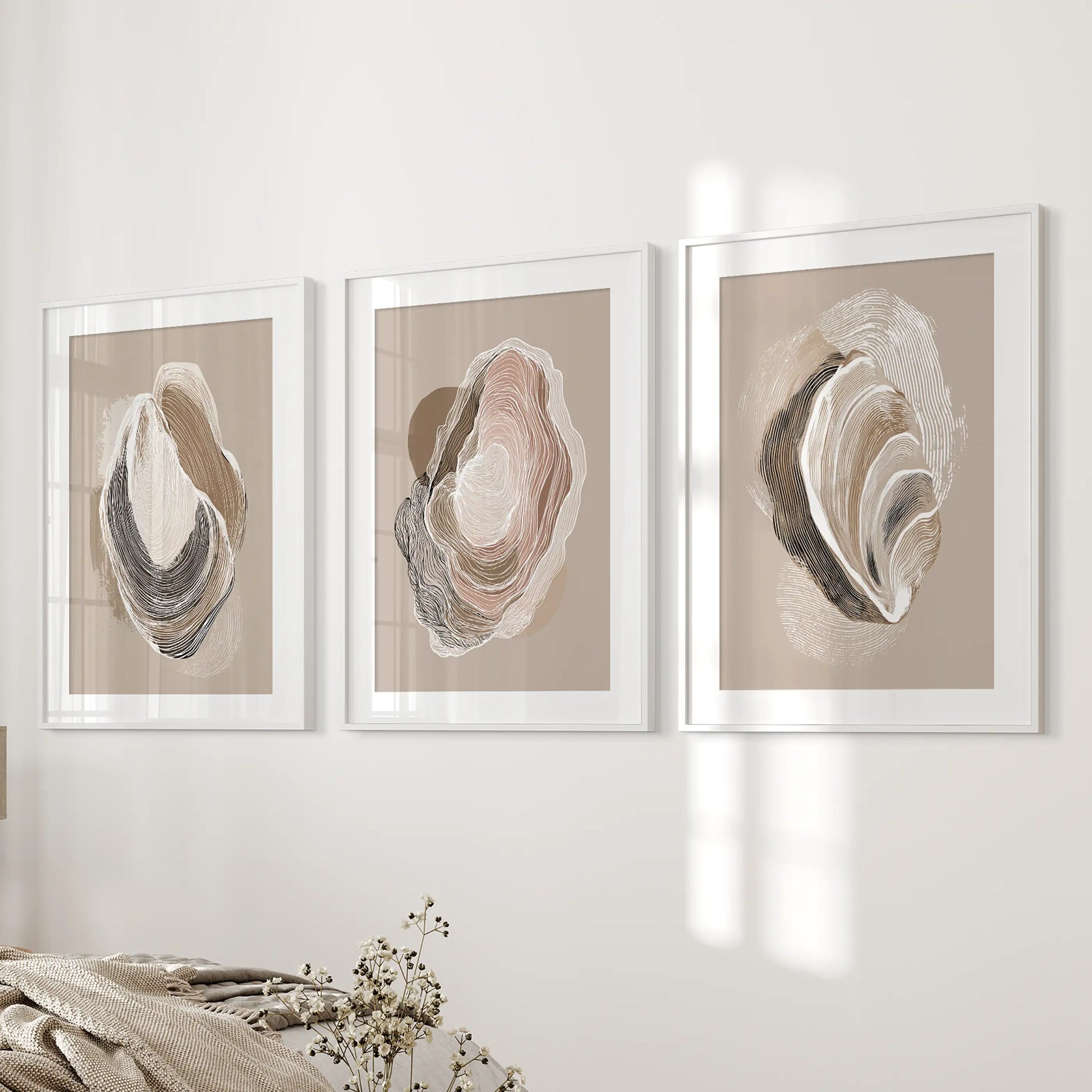 Three oyster shell sketches in white matted frames rest beside the bed, softening the bedroom with quiet coastal calm.