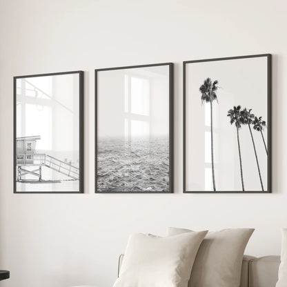 A three-piece black-framed wall art set featuring a lifeguard tower scene adds graphic coastal flair above the family-room sectional.