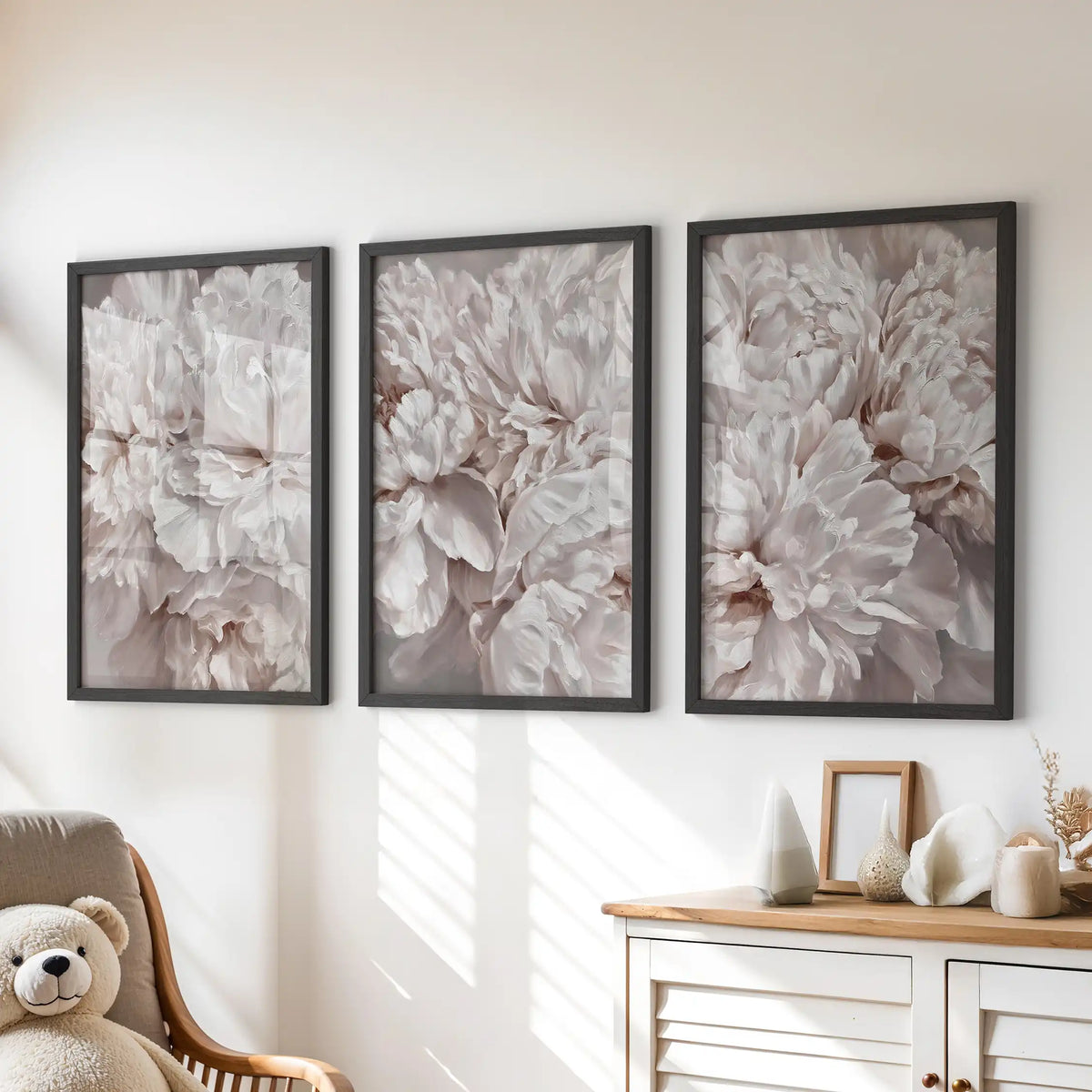 Above a dresser, three black-framed prints show pale pink peony petals.