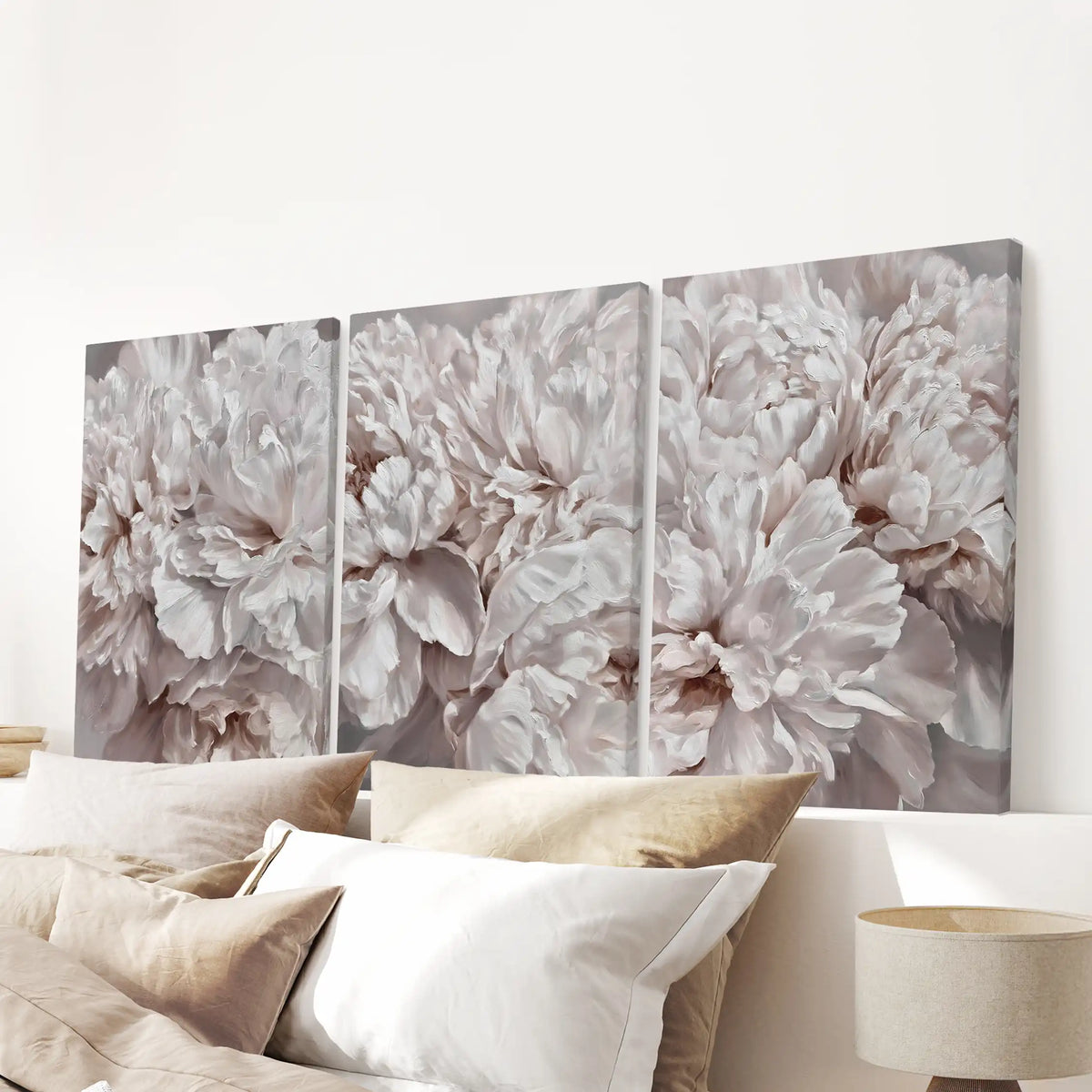 Blush peony close-ups cover three canvases above a bed.
