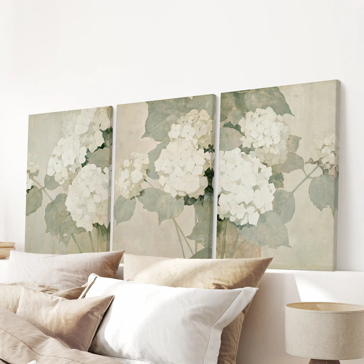 Three-print canvas wall art set of hydrangea illustrations, ready to hang and displayed over a bed in the bedroom.