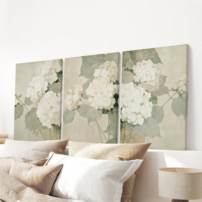 Three-print canvas wall art set of hydrangea illustrations, ready to hang and displayed over a bed in the bedroom.