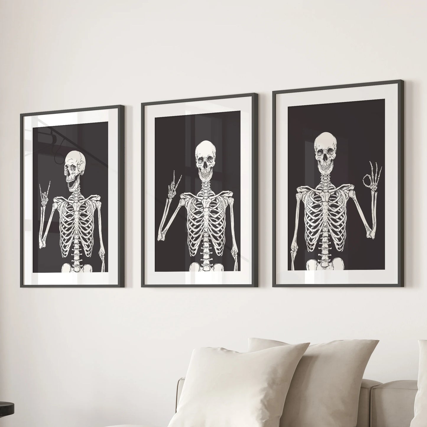 Skeleton illustrations in a 3-piece set of wall decor sit in black frames with mats, hanging over the couch in the sitting room.