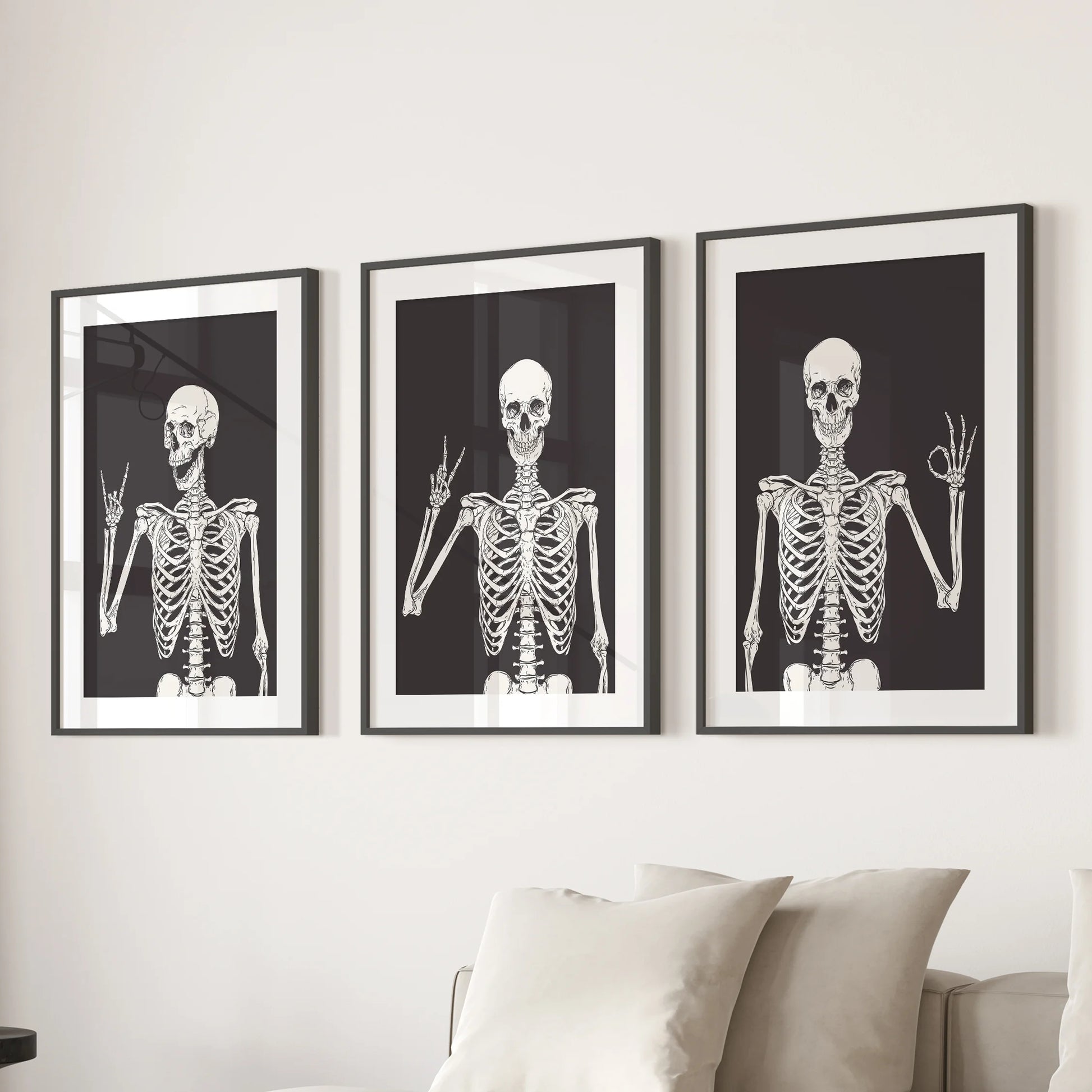 Skeleton illustrations in a 3-piece set of wall decor sit in black frames with mats, hanging over the couch in the sitting room.