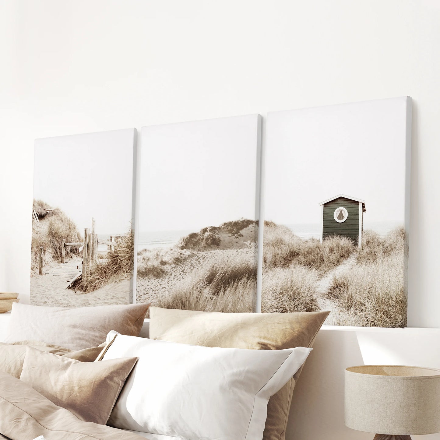 Above the headboard, three gallery-wrapped canvas prints of pampas grass move softly across the wall, lending cozy neutral calm to the room.