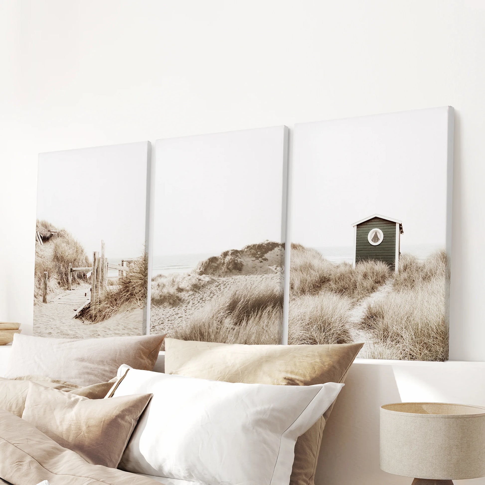 Above the headboard, three gallery-wrapped canvas prints of pampas grass move softly across the wall, lending cozy neutral calm to the room.