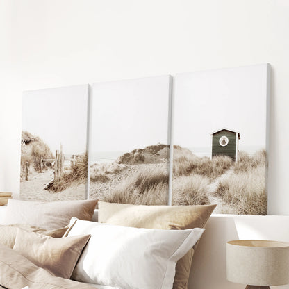 Above the headboard, three gallery-wrapped canvas prints of pampas grass move softly across the wall, lending cozy neutral calm to the room.