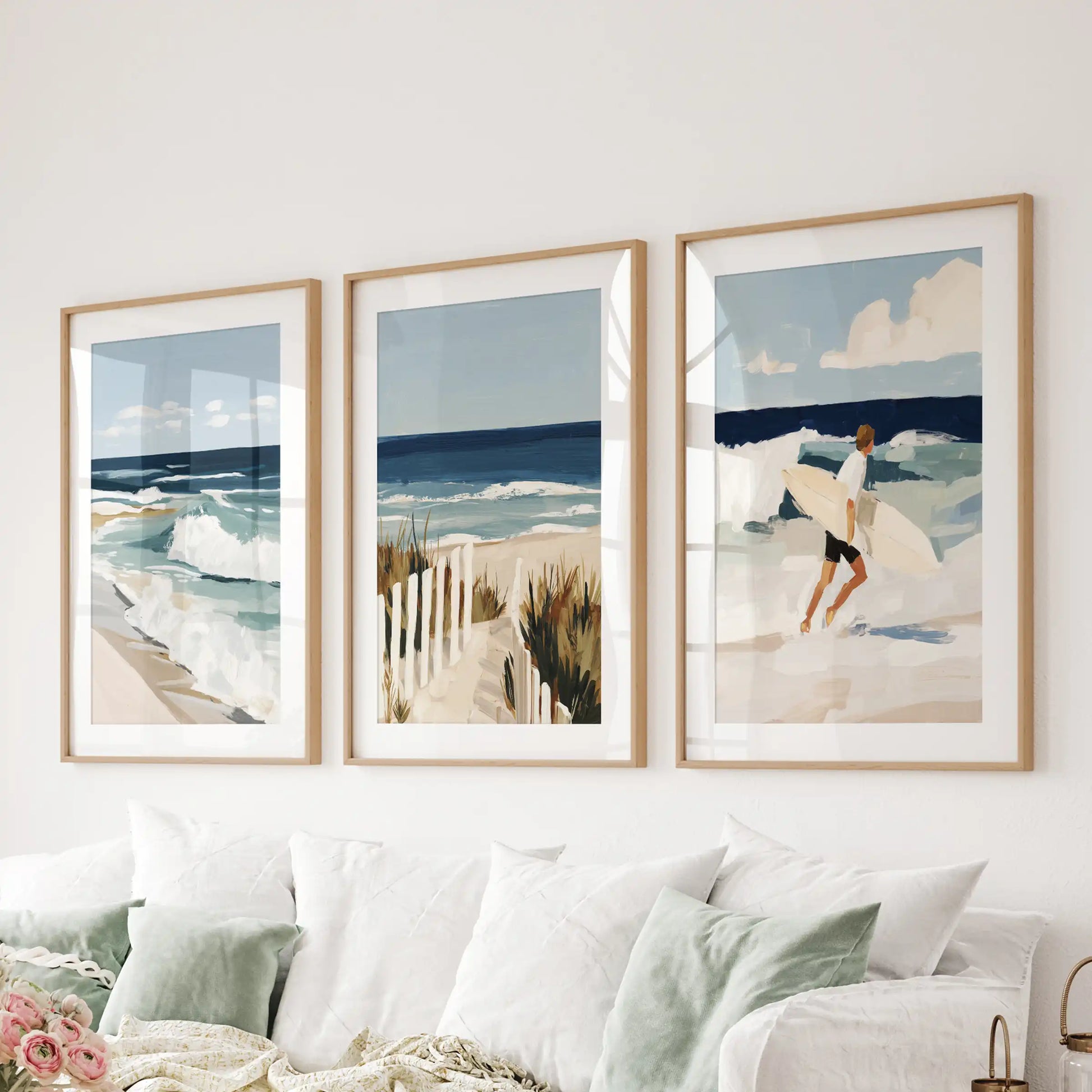 Three sunny beach path prints in natural oak frames with mats drift above the couch, filling the sitting room with dune light.
