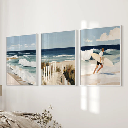 A three-print beach path art set in white frames warms the bedroom wall beside the bed with a gentle, seaside calm.