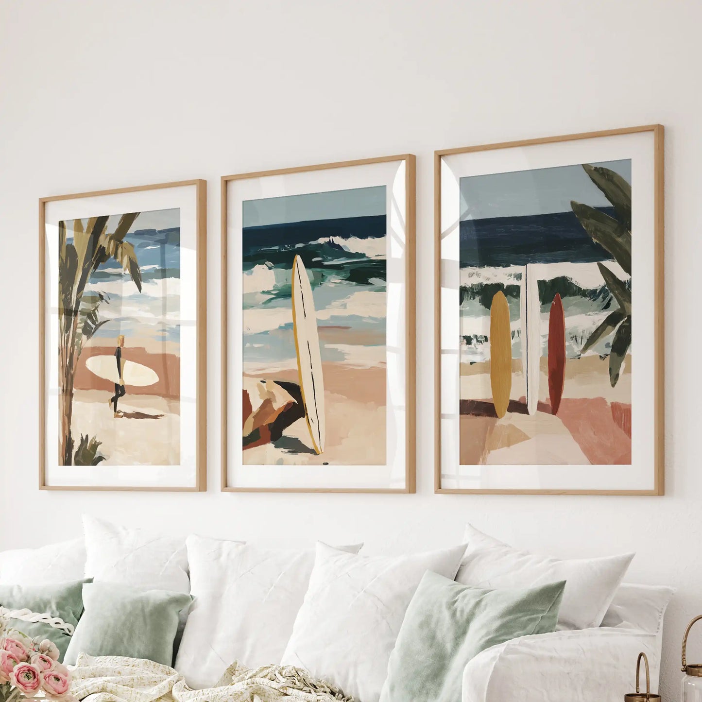 Surfers set of 3 posters in oak frames with mats hangs behind the living-room couch, capturing silhouettes carving across golden late-day swells.