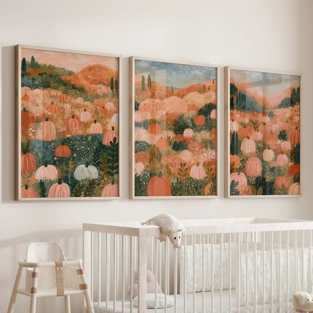 Three oak-framed wall art prints depict a farmhouse fall landscape, resting softly above the baby-room bassinet with gentle countryside hues.