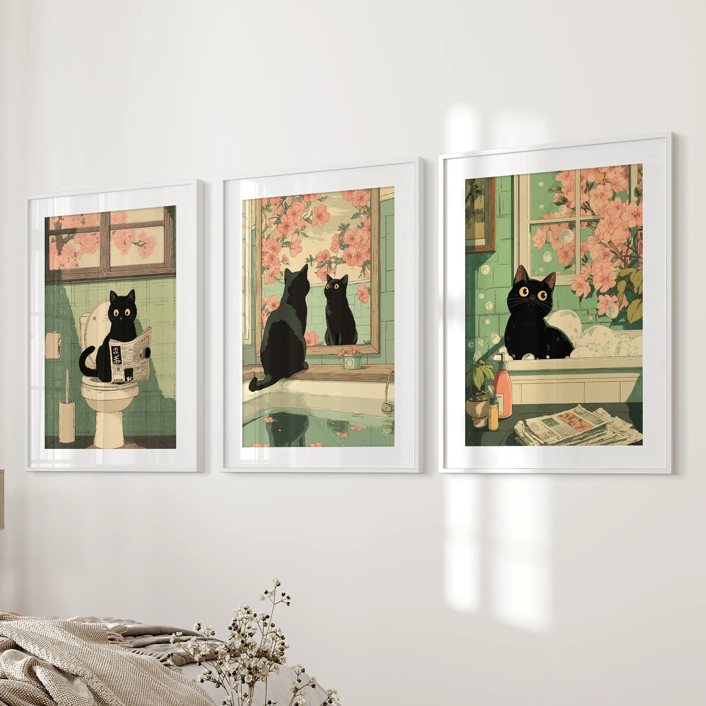 This three-panel wall art shows a toilet-reading black cat in white framed prints with mats, displayed beside the bed for subtle humor.