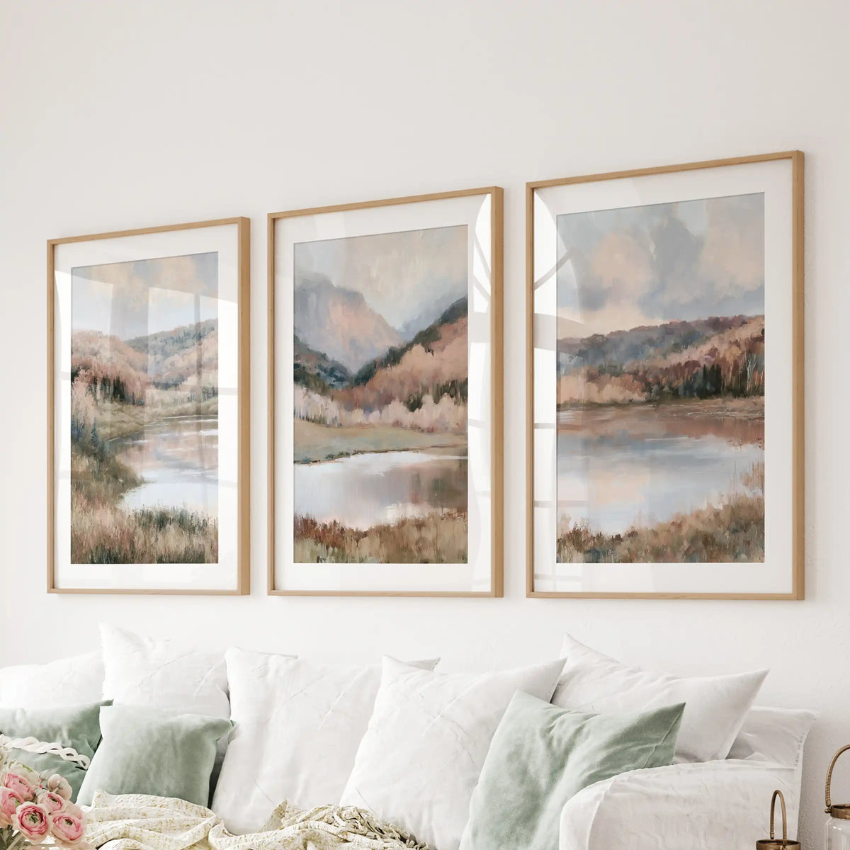 A three-print gallery of soft autumn nature scenes in natural wood matted frames spans the lounge wall above the sectional for a cohesive look.