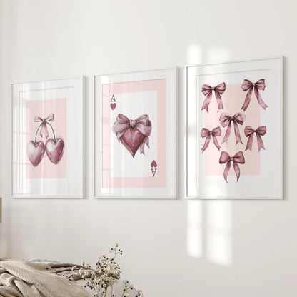 Coquette icon trio 3-piece wall art set-ace, bows, cherries-in white frames with mats hangs beside the bed, tying the bedroom palette together.