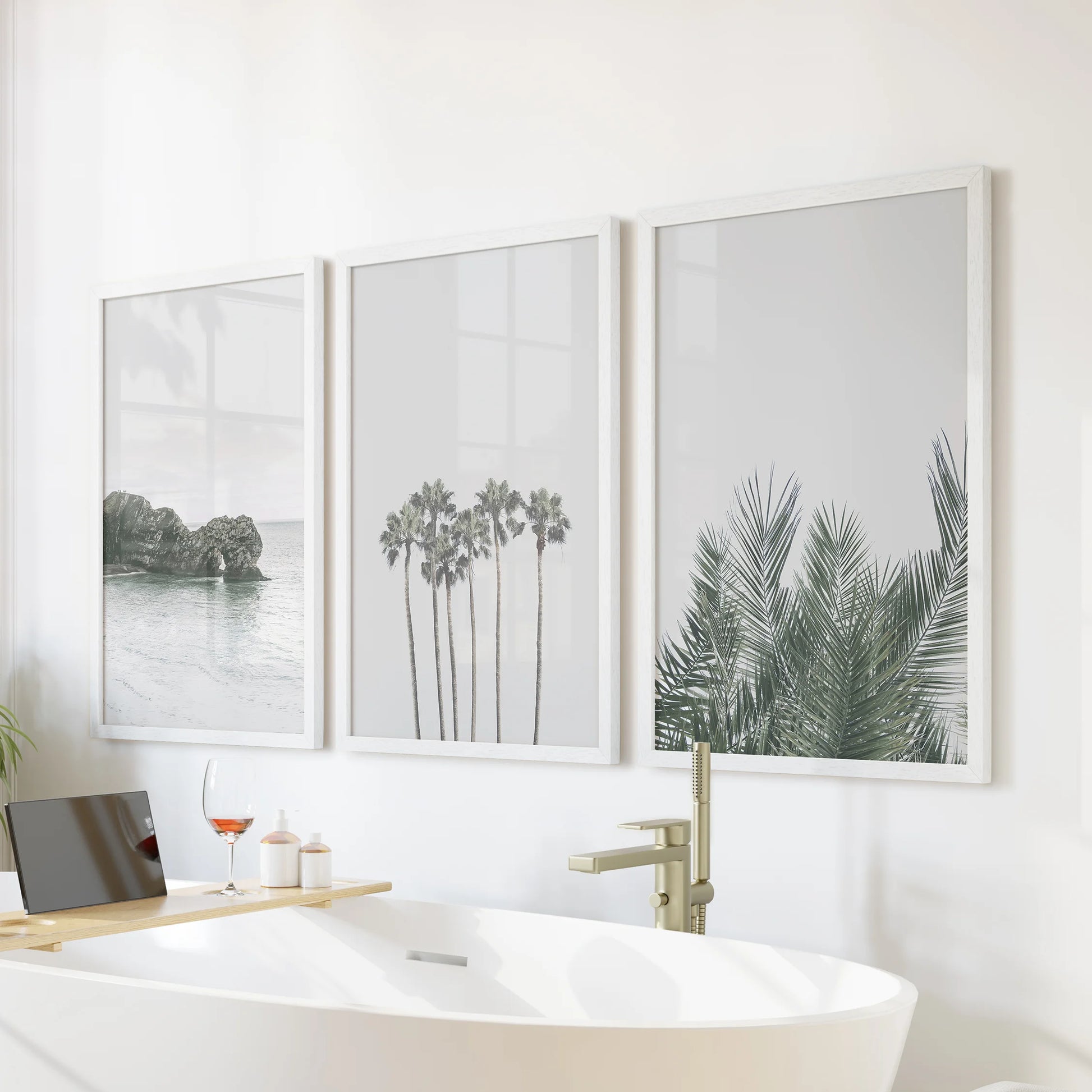 Set of three California sunset posters in white frames hangs neatly above the bath, infusing peaceful seaside light throughout the bathroom.