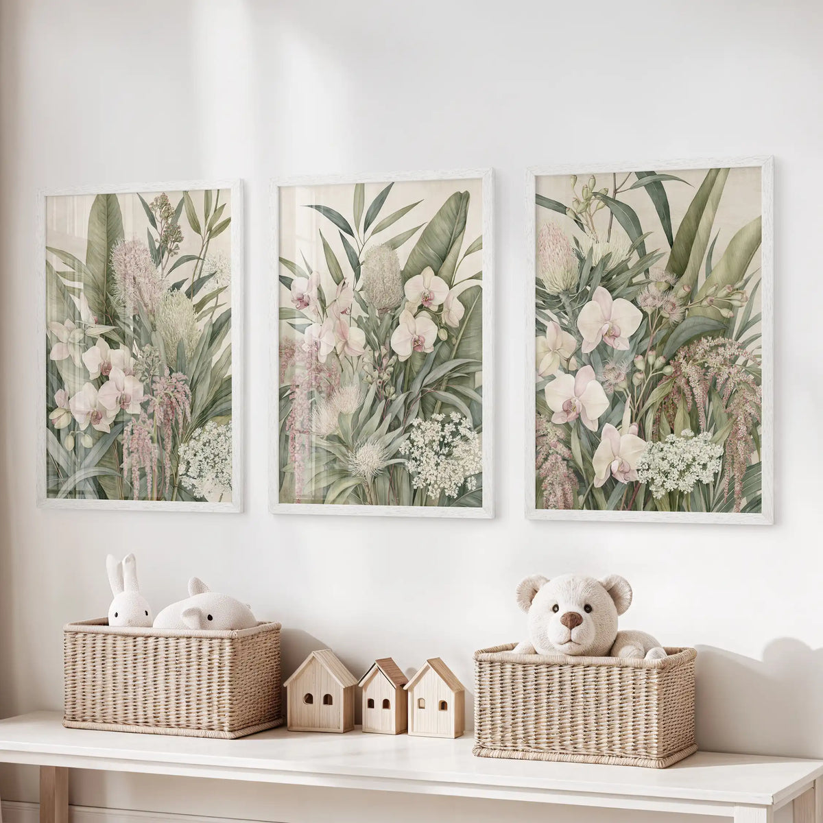 The three white-framed prints above toy baskets show pale pink orchids, overlapping green leaves and small clusters of white flowers.