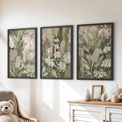 Pale orchids and upright green leaves appear above a dresser in three black-framed prints, with mottled beige behind the layered plants.