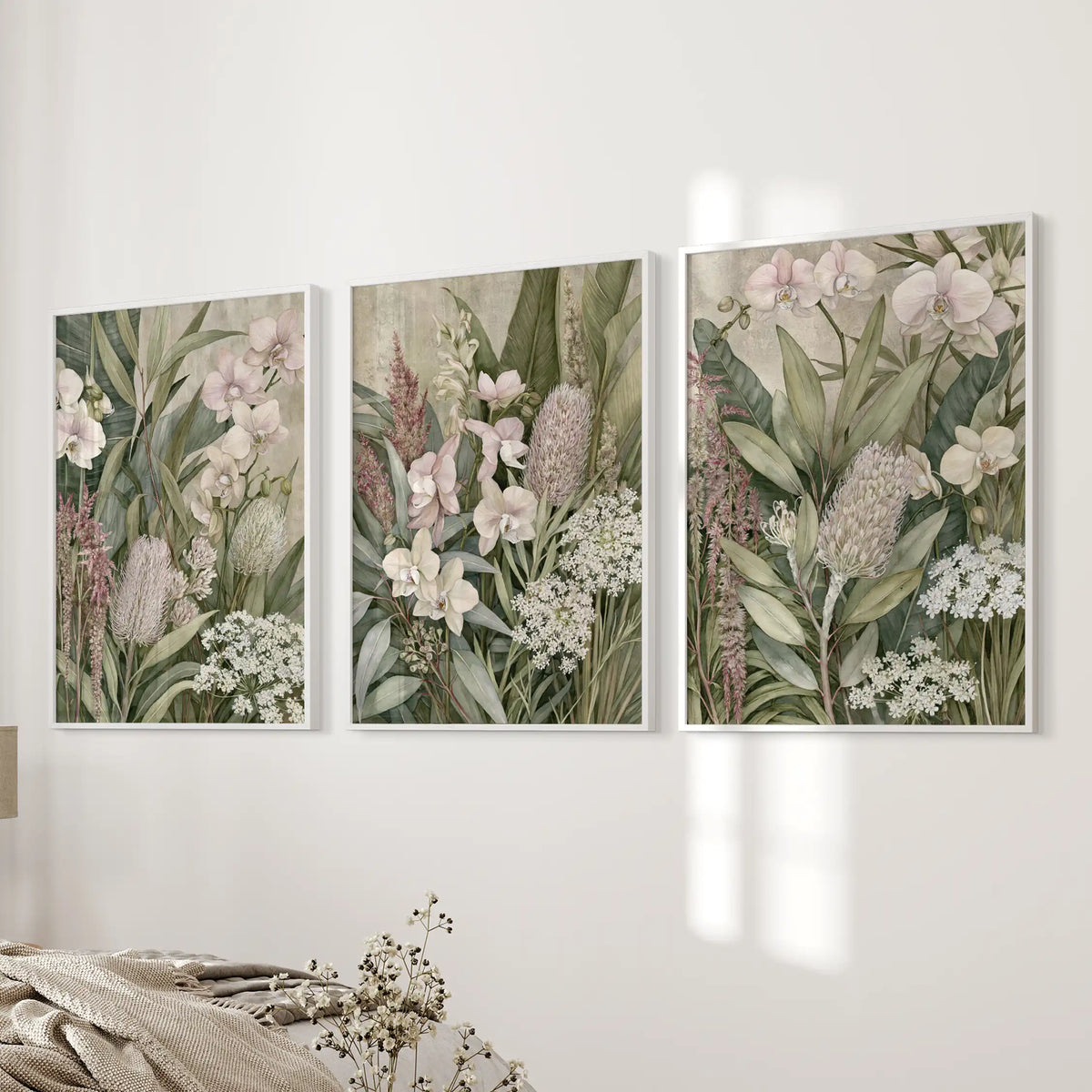 Tropical botanical prints fill three white frames beside a bed.