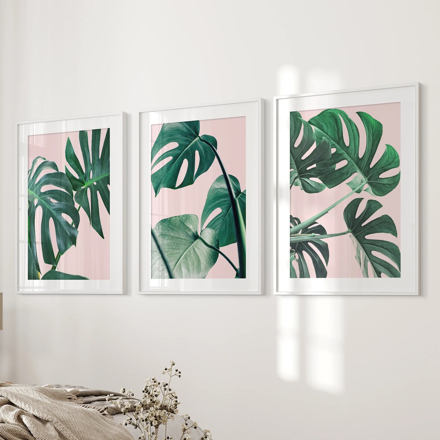Framed in white with matting, this three-piece set of pink tropical plant prints stretches beside the bed as airy, modern wall art.