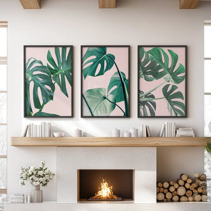 A trio of black-framed posters featuring pink monstera leaves forms striking wall art above the living room mantel, lending a lush, modern tone.