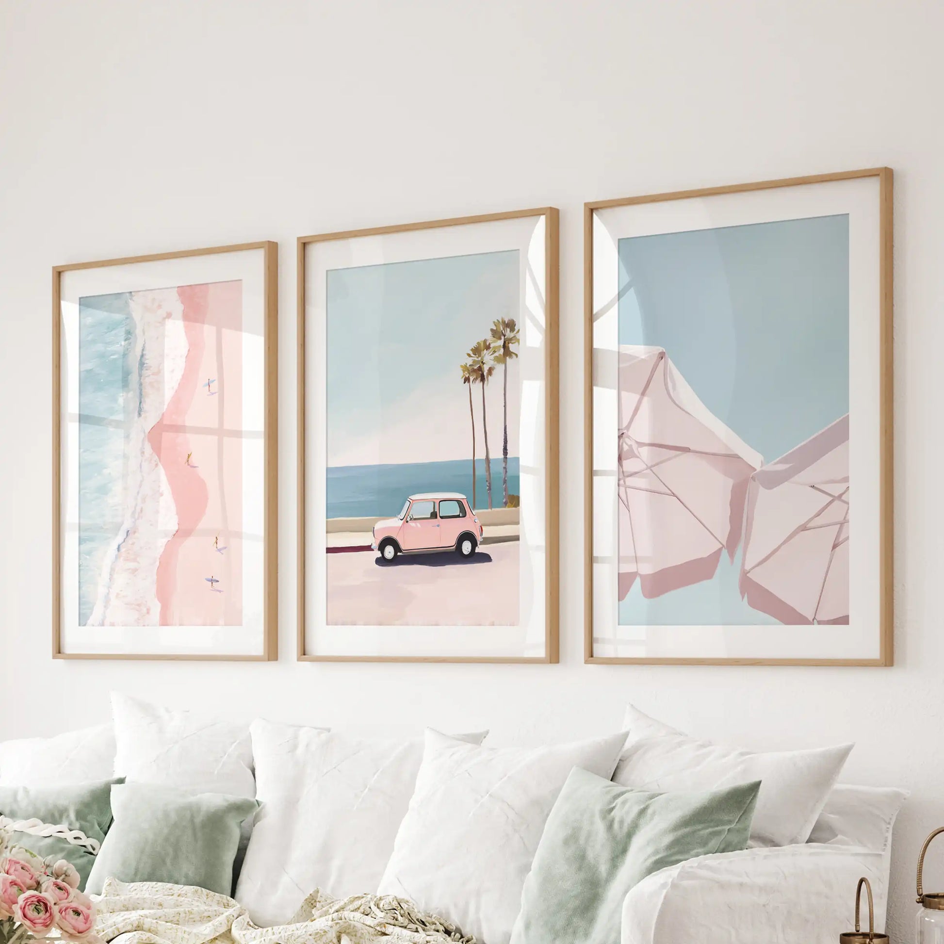 Pink coastal beach scenes, a wall-hanging set of three in natural oak frames with mats, glow softly over the couch in the living room.