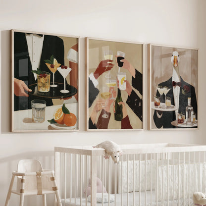 Vintage cocktail bar wall art in a gallery set of three, arranged in light wood frames over a bassinet in a baby's room.