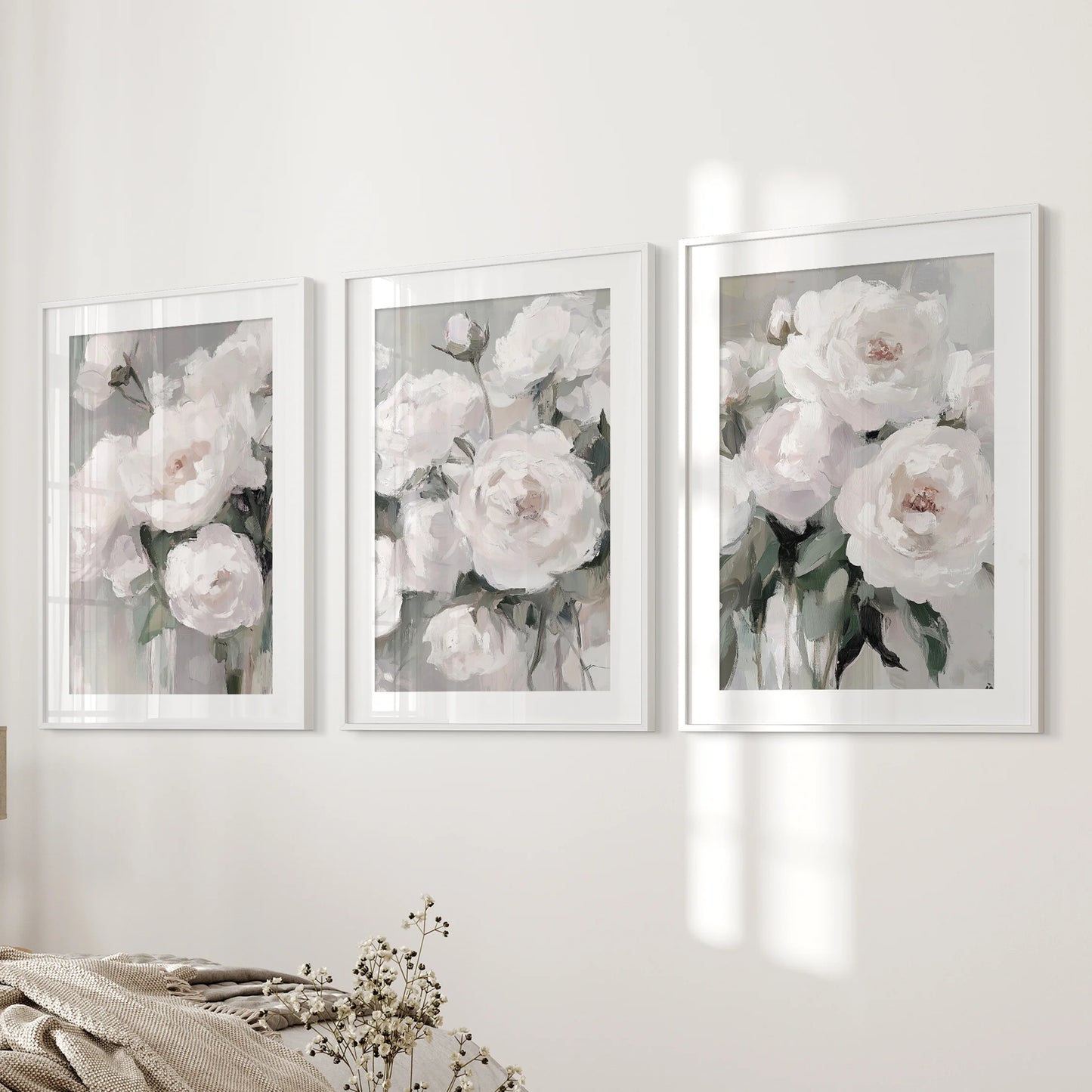 Abstract peony blossoms form a 3-piece artwork set, white-mat frames lining the bedroom wall beside the bed with painterly texture and quiet romance.