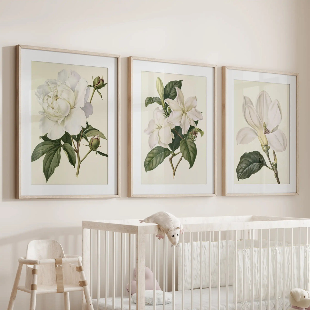 Oak frames with white mats hold three white flower prints above a crib.