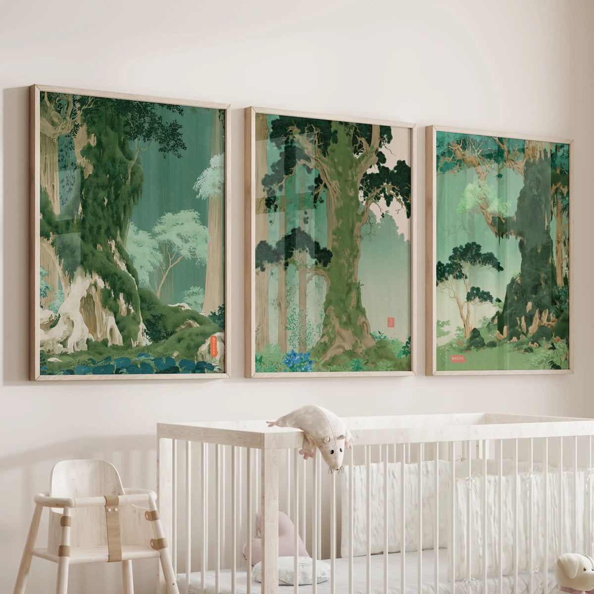 A set of three vintage Japanese forest wall prints in light oak frames hangs above a bassinet in the baby room.