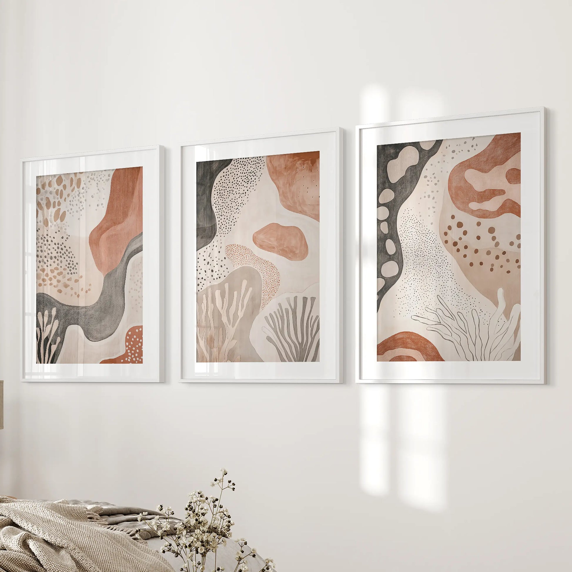 Terracotta geometric patterns, 3-piece wall decor in white matted frames, lend a calm, cohesive look to the bedroom wall.
