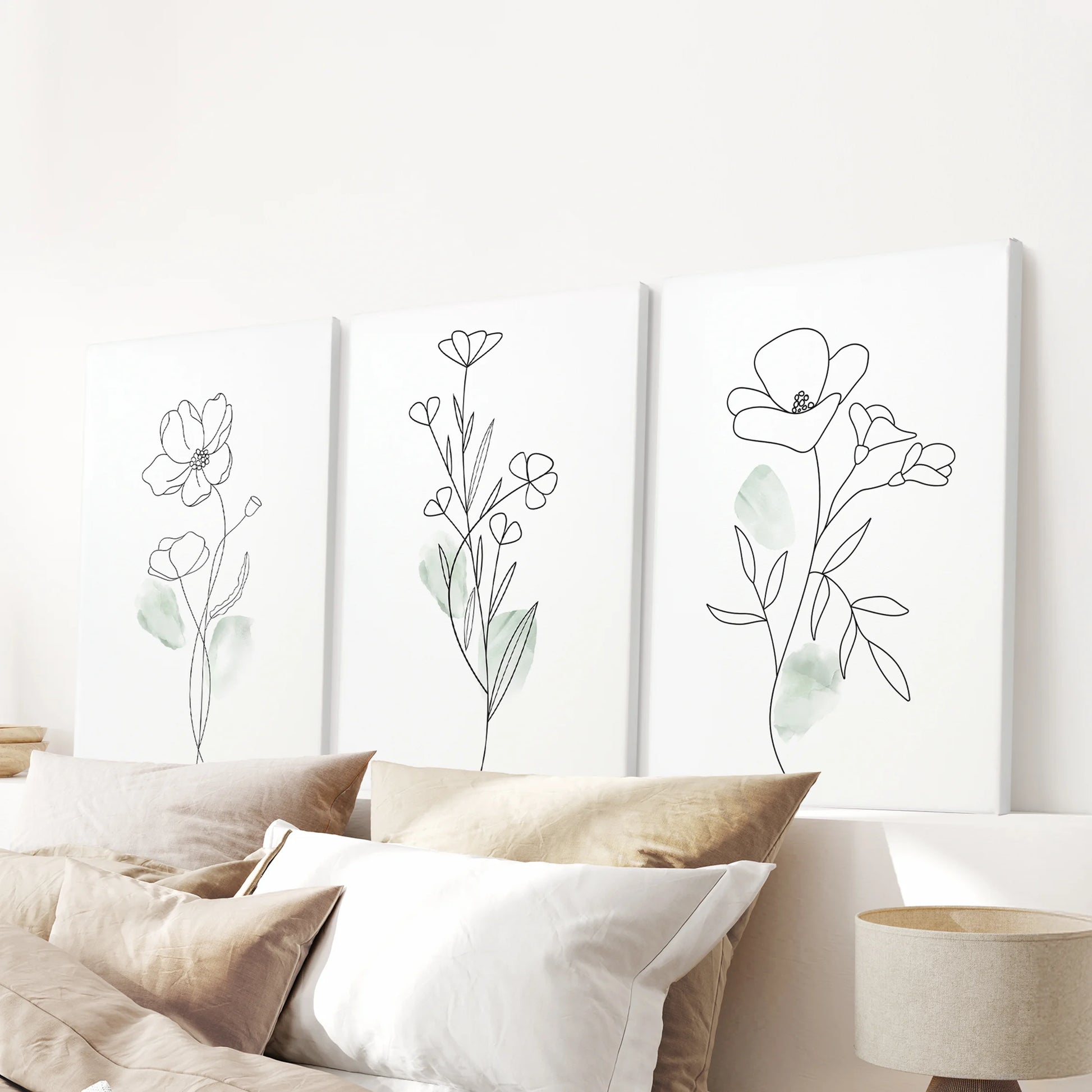 Three frameless watercolor floral posters float above the headboard, canvas texture adding depth to the soft green palette and serene look.