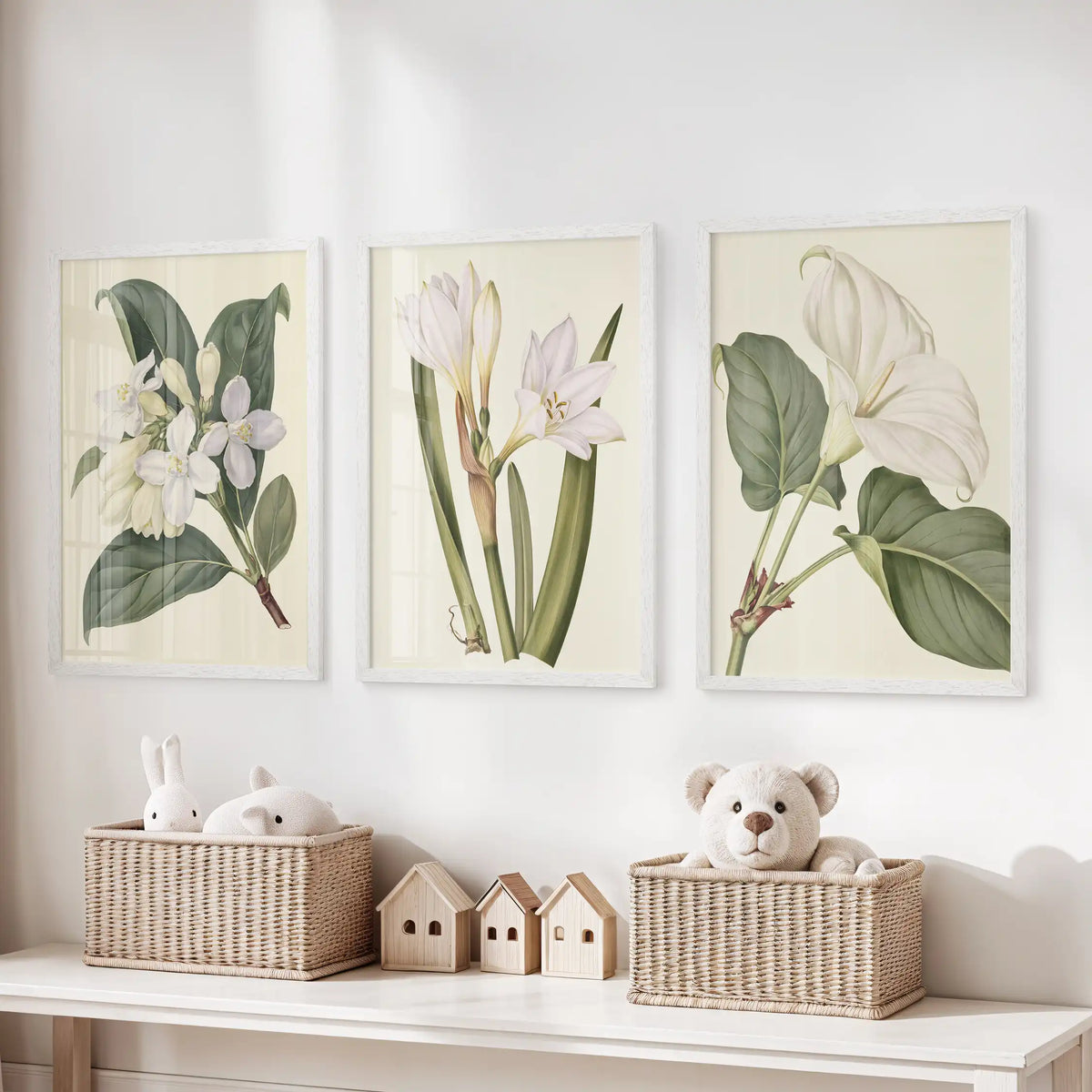 Green and white botanical wall art in three white frames above a toy storage bench.