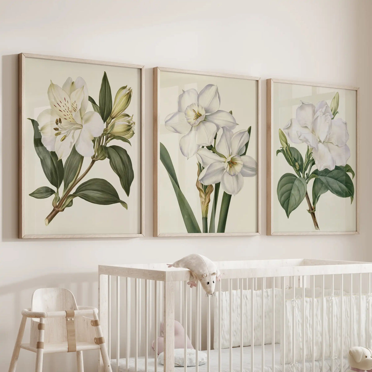 White flower prints hang in three oak frames above a nursery crib, with narcissus in the middle.