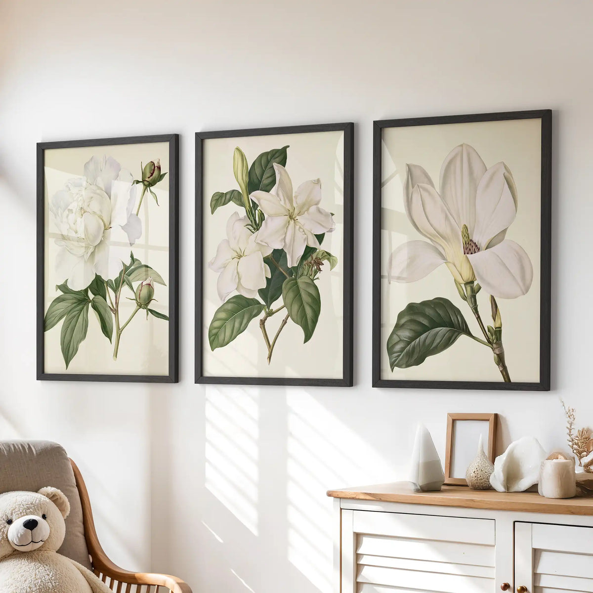 The three prints above a dresser show a ruffled white bloom, smaller blossoms and an open flower, with dark green leaves inside black frames.